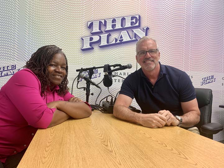 Cynthia Thompson and Mark Smith with microphones and The Plan podcast background